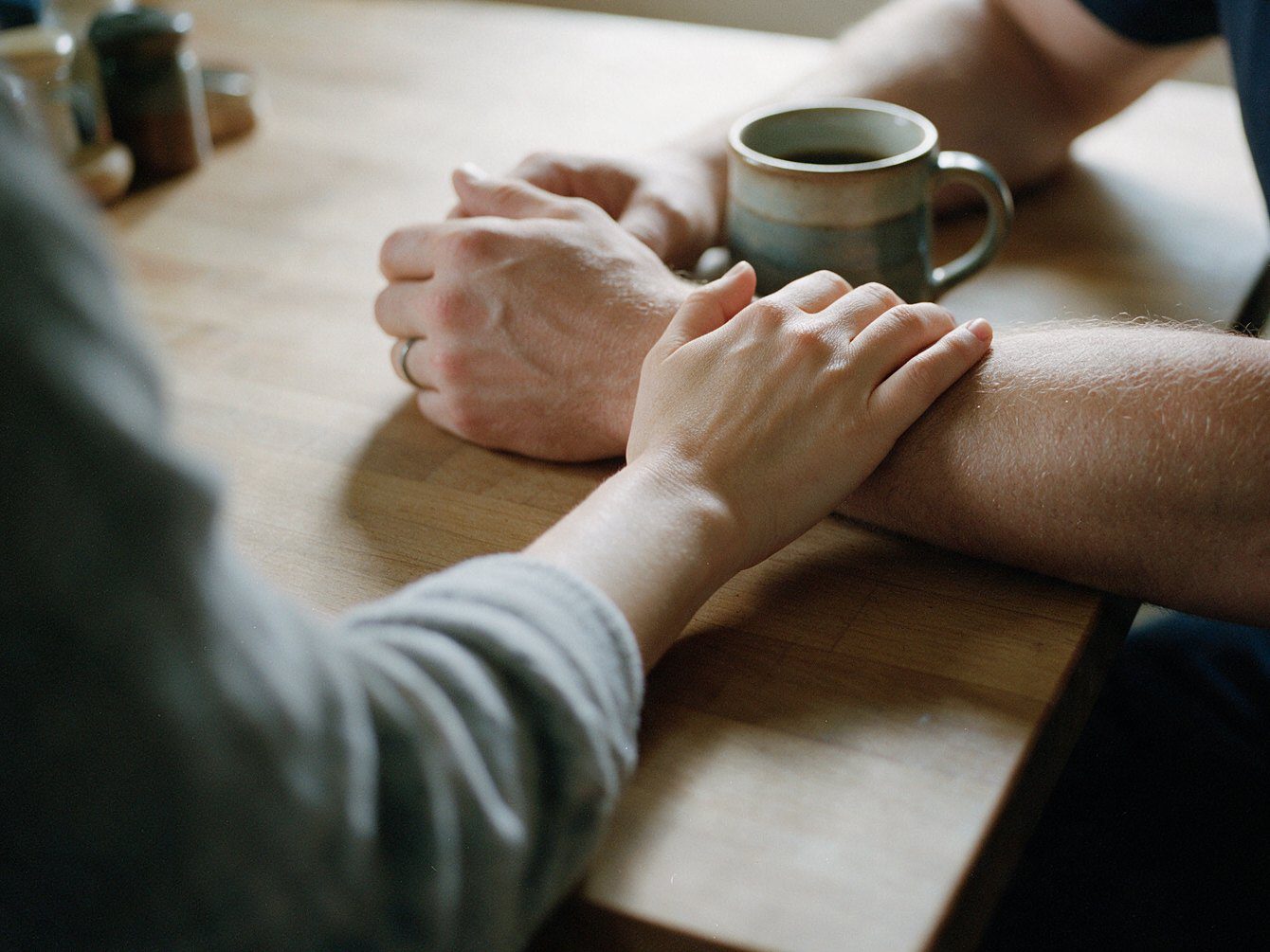 A family member’s hand resting on a firefighter’s forearm at the kitchen table