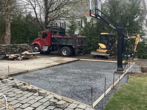 Landscape construction in progress: gravel base and cobblestone edging for a new sport court