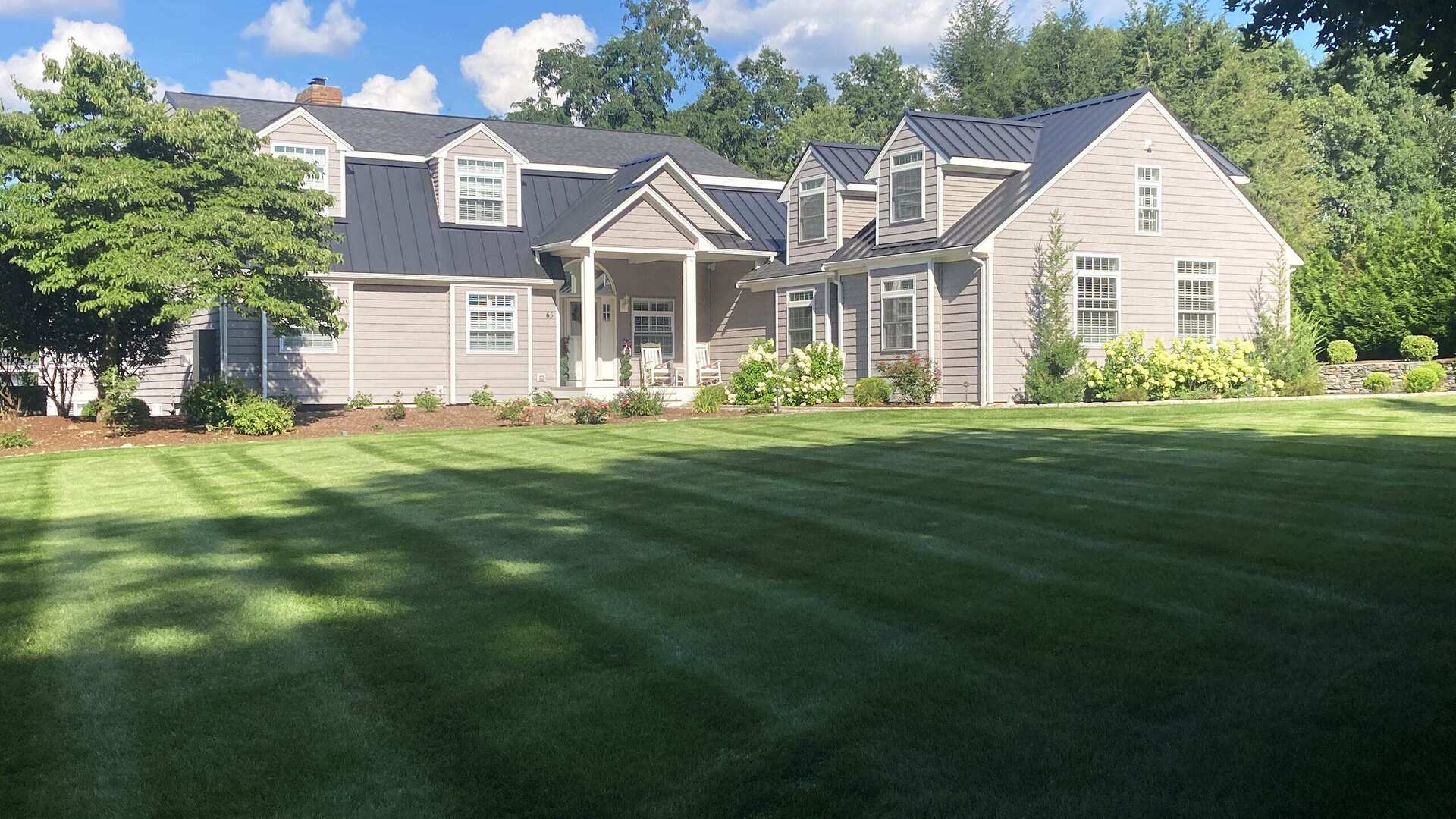 Freshly striped lawn and foundation plantings maintained by Ten Four in Franklin, MA