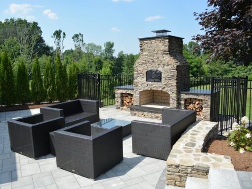 Stone outdoor fireplace and wicker seating on a paver patio