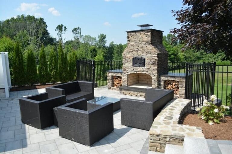 Outdoor living space with a stone fireplace and seating by Ten Four Landscape & Construction in Wrentham, Norfolk, Franklin & Foxboro, MA