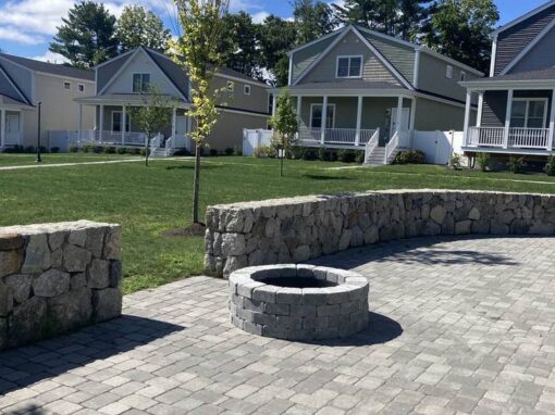 Round fire pit and curved fieldstone seat wall on a paver patio