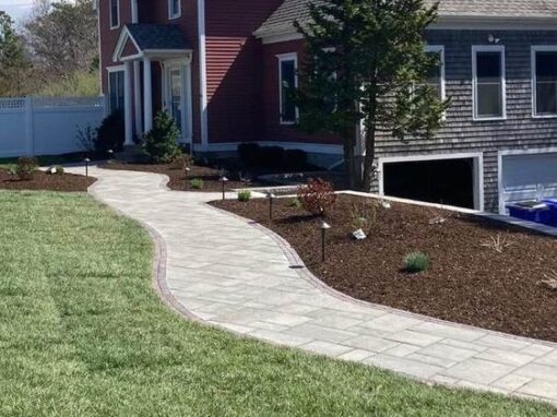 Curved paver path through new sod to a red colonial, one of our patios and walkways jobs