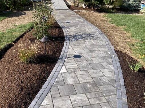 Paver path with a charcoal border running between fresh mulch beds