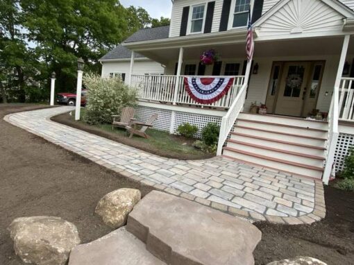 Wide paver walk and natural stone slab steps up to a farmhouse porch, part of our patios and walkways work