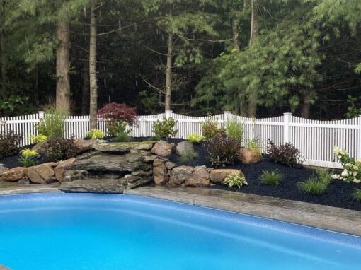 Poolside planting bed around a rock waterfall with grasses and perennials