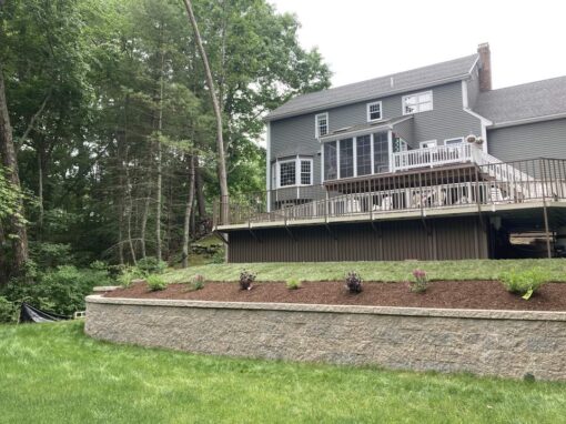 Block retaining wall with a raised mulch bed below a deck
