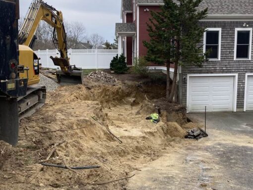 Excavator digging a trench beside a driveway