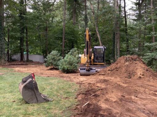 Excavator trenching across a yard, the first step in many water drainage solutions