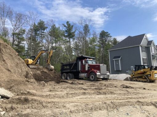 Dump truck, excavator and skid steer grading a new home lot