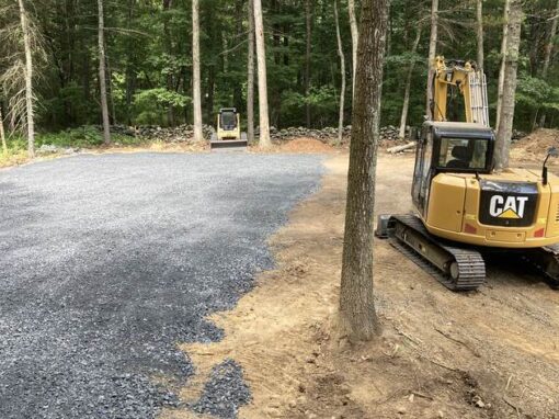 Sitework in the woods: excavator clearing and grading for a gravel drive