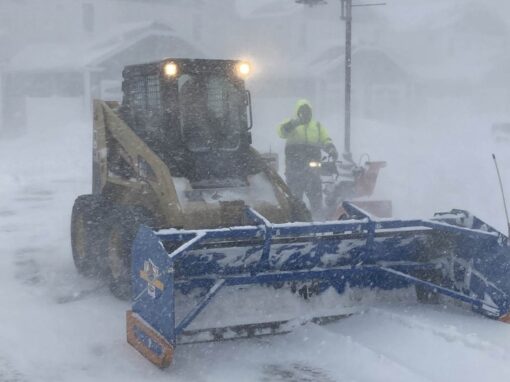 Skid steer plowing snow during a storm