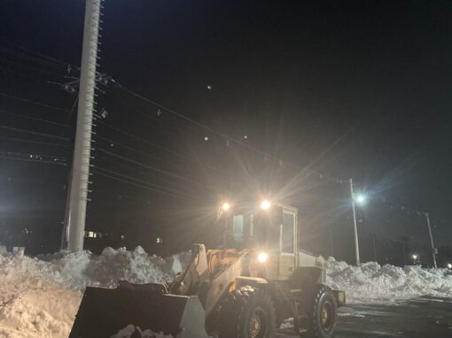 Loader working a retail parking lot overnight under the lights