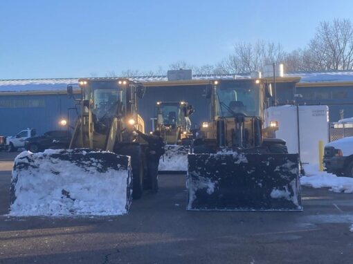 Two loaders with pushers staged in a commercial lot