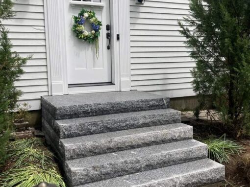 Granite block steps and lanterns at a white front door