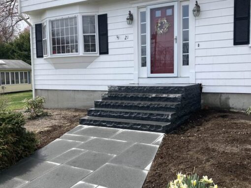 Dark stone stoop and bluestone walk at a white colonial entrance