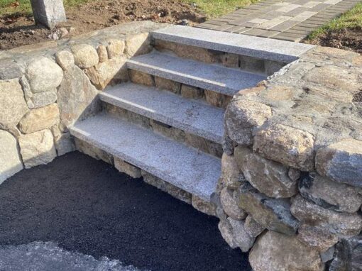 Granite steps set between fieldstone walls off an asphalt driveway