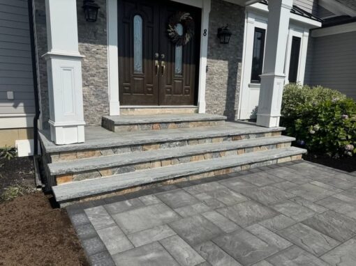 Wide bluestone treads with stone veneer risers and a paver landing at a double front door